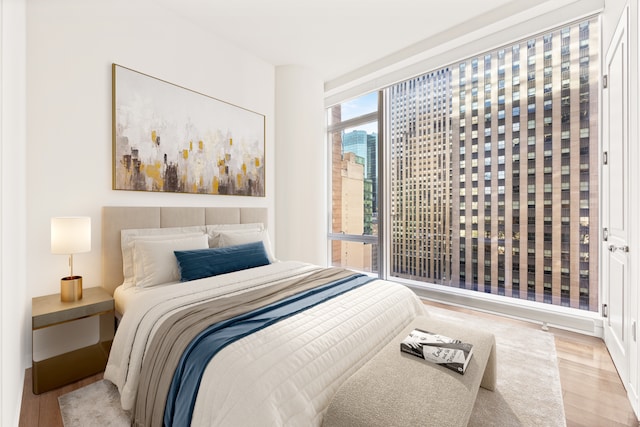 bedroom featuring a view of city and wood finished floors