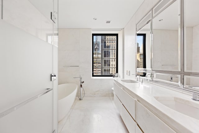 bathroom featuring tile walls, vanity, a washtub, and a wealth of natural light