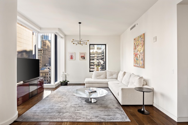 living area with plenty of natural light, baseboards, dark wood finished floors, and a notable chandelier