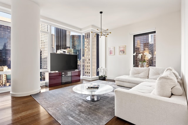 living room with a healthy amount of sunlight, dark wood-type flooring, and an inviting chandelier