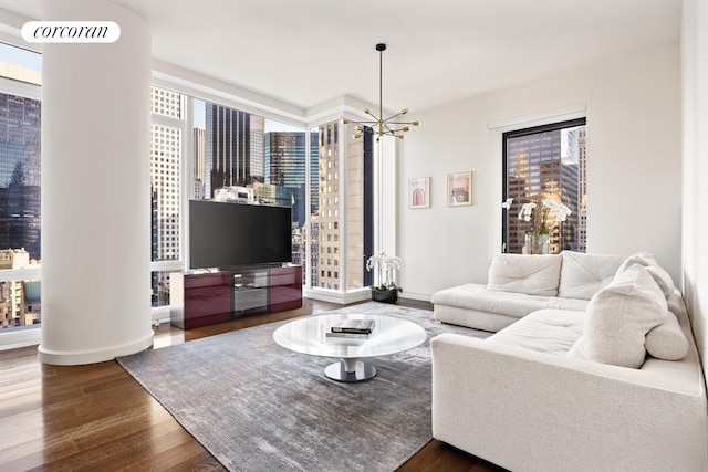 living area with a notable chandelier, wood finished floors, visible vents, baseboards, and floor to ceiling windows