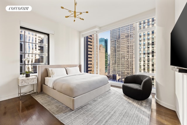 bedroom with multiple windows, wood-type flooring, and an inviting chandelier