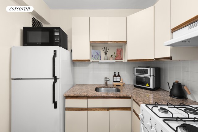 kitchen featuring sink, white appliances, white cabinetry, tasteful backsplash, and dark stone counters