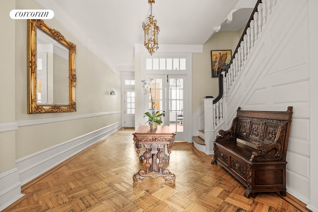 foyer with a chandelier, stairway, and a wainscoted wall