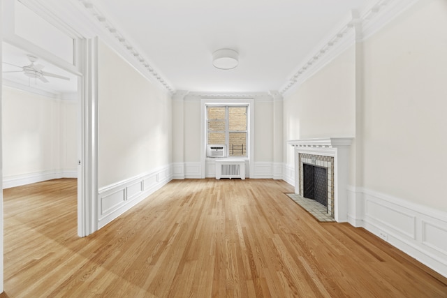 unfurnished living room featuring crown molding, ceiling fan, radiator heating unit, and light wood-type flooring