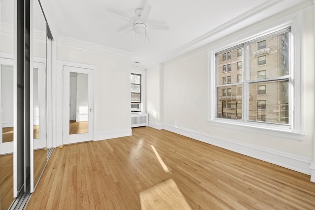 unfurnished bedroom with baseboards, radiator, ceiling fan, ornamental molding, and light wood-style floors