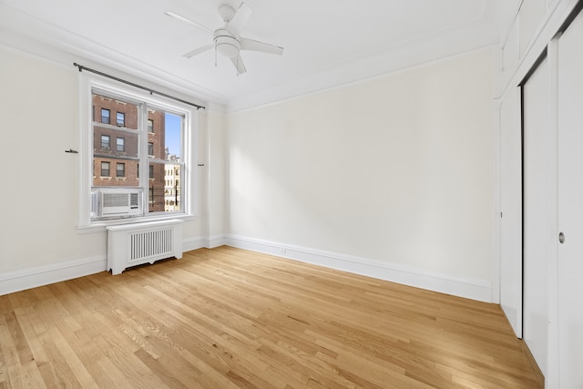 unfurnished room featuring light wood finished floors, baseboards, radiator, ceiling fan, and cooling unit