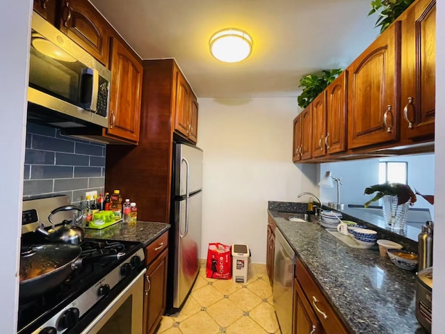 kitchen featuring dark stone countertops, backsplash, sink, and appliances with stainless steel finishes