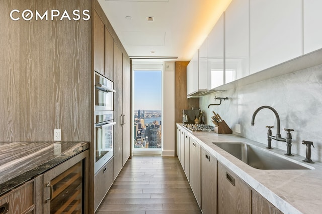 kitchen with a sink, stainless steel appliances, dark wood-type flooring, decorative backsplash, and white cabinetry