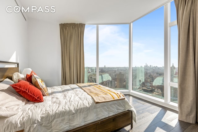 bedroom featuring wood finished floors, expansive windows, and a city view