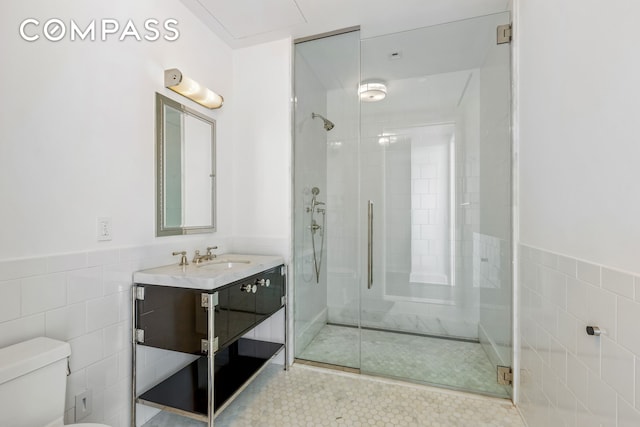full bathroom featuring tile walls, toilet, a shower stall, vanity, and wainscoting