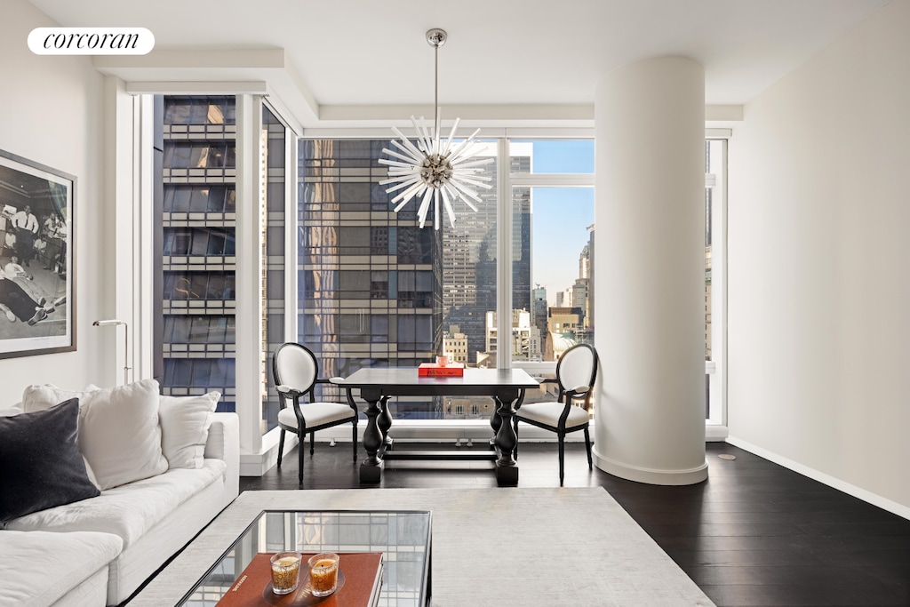 living area featuring visible vents, dark wood-type flooring, a city view, an inviting chandelier, and baseboards