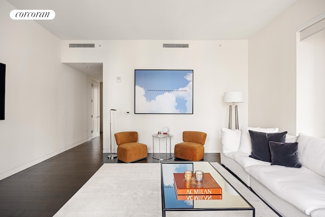 living area featuring baseboards, visible vents, and wood finished floors