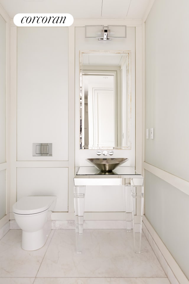 half bath with marble finish floor, toilet, and vanity