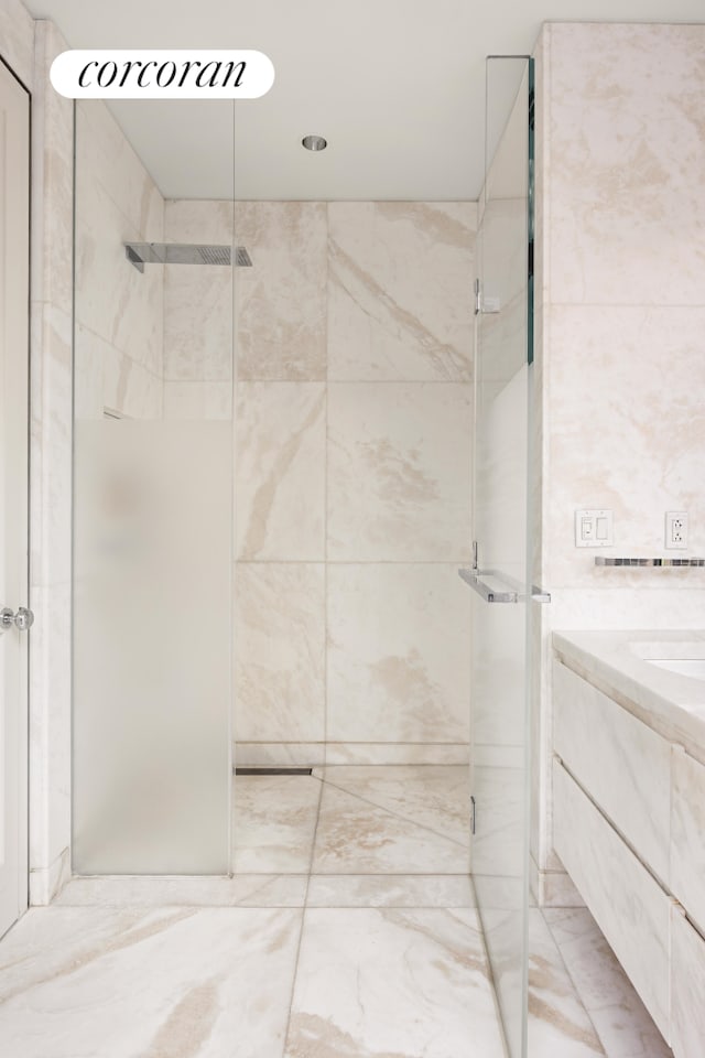 bathroom with tile walls, a shower stall, and vanity