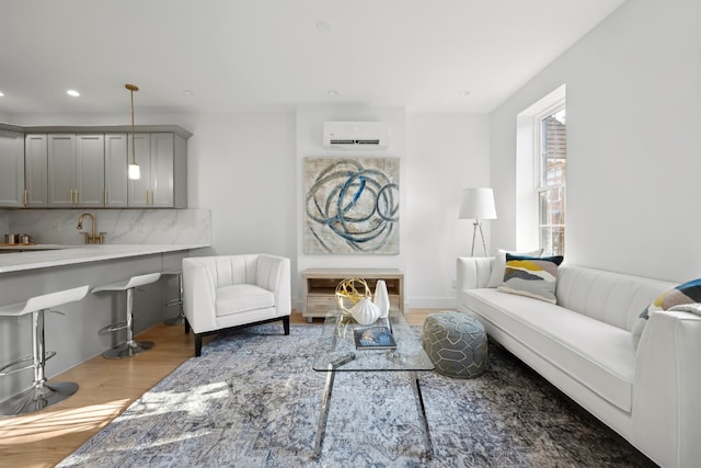 living room with hardwood / wood-style flooring, sink, and a wall mounted AC