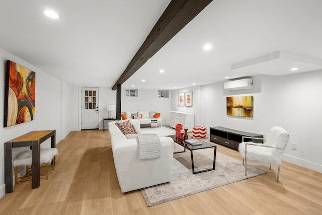 living room featuring beam ceiling, a wall unit AC, and light hardwood / wood-style floors