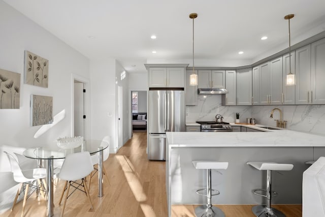 kitchen featuring gray cabinets, decorative light fixtures, sink, kitchen peninsula, and stainless steel appliances