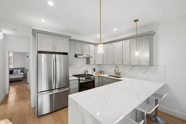 kitchen with stainless steel appliances, gray cabinets, pendant lighting, and backsplash