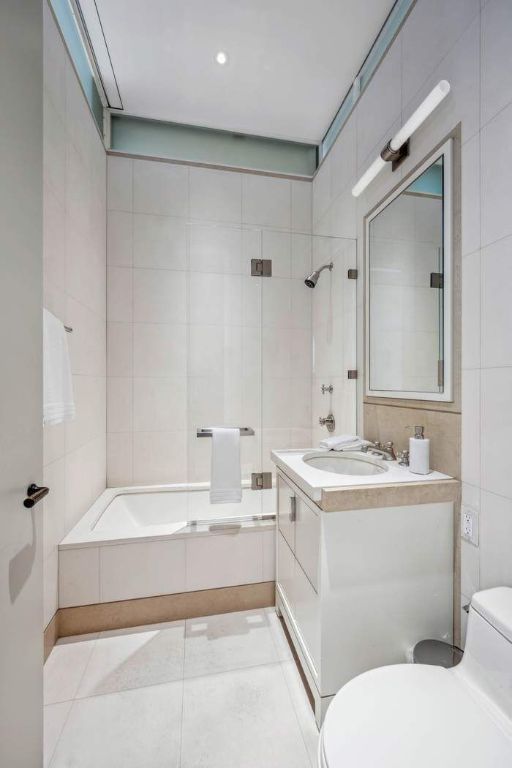 full bathroom with toilet, tile walls, vanity, tiled shower / bath combo, and tile patterned flooring