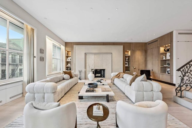 living room featuring light hardwood / wood-style flooring, wood walls, and built in shelves