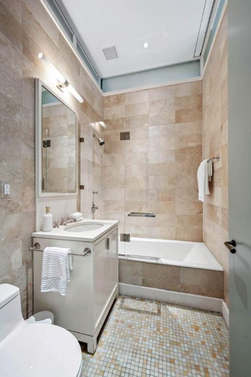 full bathroom with tiled shower / bath, vanity, toilet, and tile walls