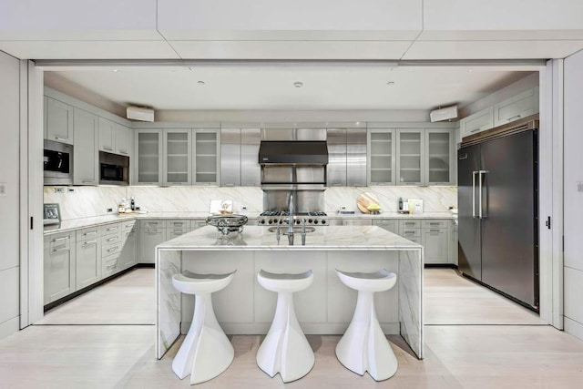 kitchen with extractor fan, a kitchen island, a breakfast bar area, decorative backsplash, and built in appliances