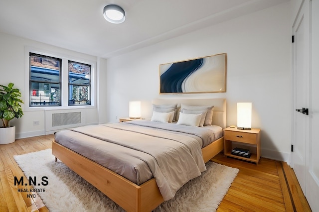 bedroom with radiator and light hardwood / wood-style floors