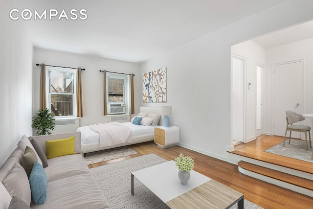 bedroom with cooling unit, wood finished floors, and baseboards