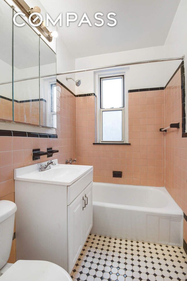 full bathroom featuring tile walls, vanity, tile patterned floors, toilet, and tiled shower / bath