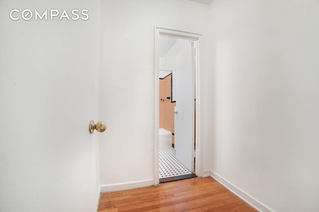 hallway featuring light wood-style flooring and baseboards