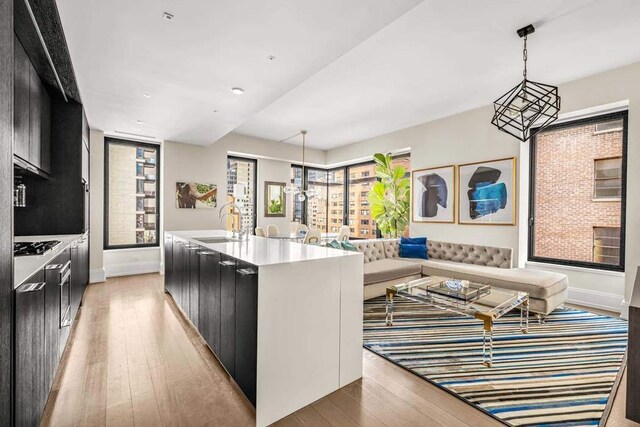 kitchen with sink, an island with sink, hanging light fixtures, and light hardwood / wood-style flooring