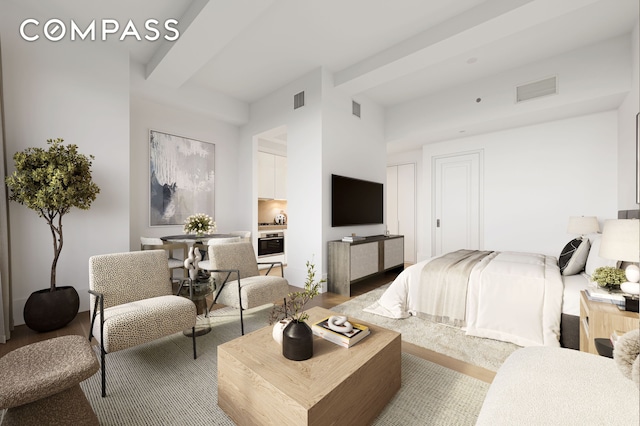 bedroom with visible vents, beam ceiling, and wood finished floors