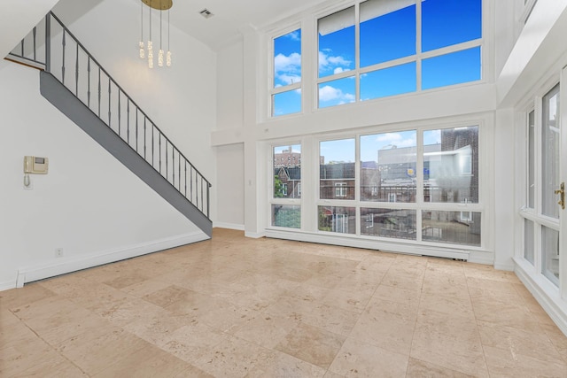 unfurnished living room featuring stairway, baseboards, visible vents, an inviting chandelier, and a view of city