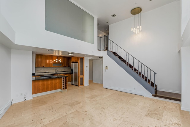 living area featuring visible vents, a notable chandelier, a high ceiling, baseboards, and stairs