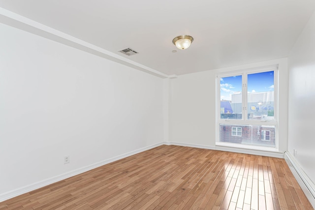 unfurnished room with visible vents, baseboards, light wood-style flooring, and a baseboard radiator