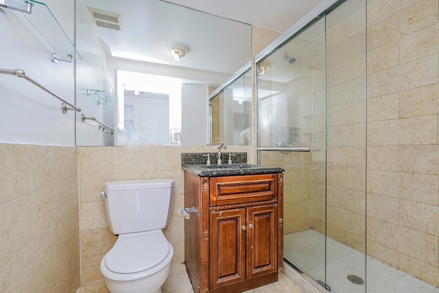 bathroom with visible vents, toilet, a stall shower, tile walls, and vanity