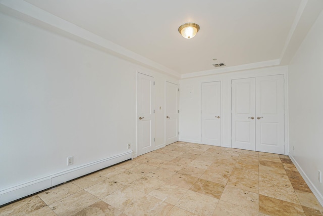 unfurnished bedroom featuring a closet, baseboard heating, baseboards, and visible vents