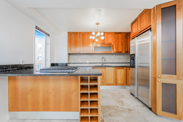 kitchen featuring a notable chandelier, a sink, appliances with stainless steel finishes, a peninsula, and decorative backsplash