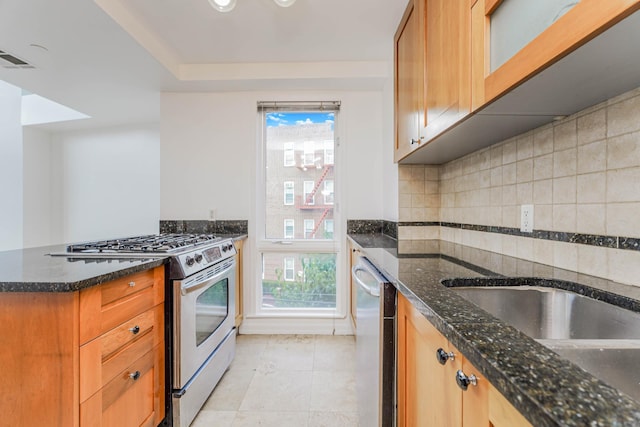 kitchen featuring light tile patterned floors, dark stone counters, plenty of natural light, stainless steel appliances, and decorative backsplash