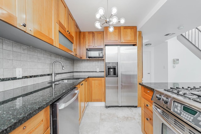 kitchen with a sink, decorative light fixtures, dark stone countertops, backsplash, and stainless steel appliances