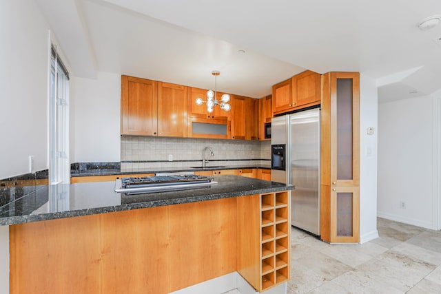 kitchen with a sink, stainless steel appliances, pendant lighting, backsplash, and a chandelier