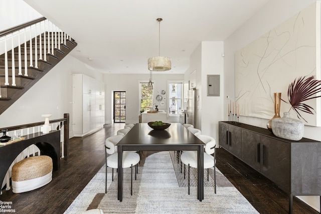 dining area featuring electric panel, stairway, and wood finished floors