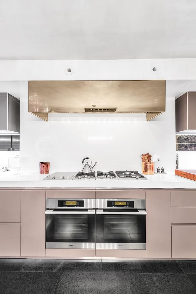 kitchen with light countertops, granite finish floor, range hood, and oven