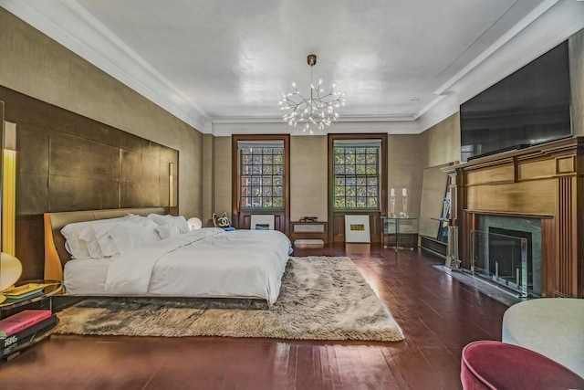 bedroom with dark wood-style floors, a notable chandelier, a fireplace, and ornamental molding