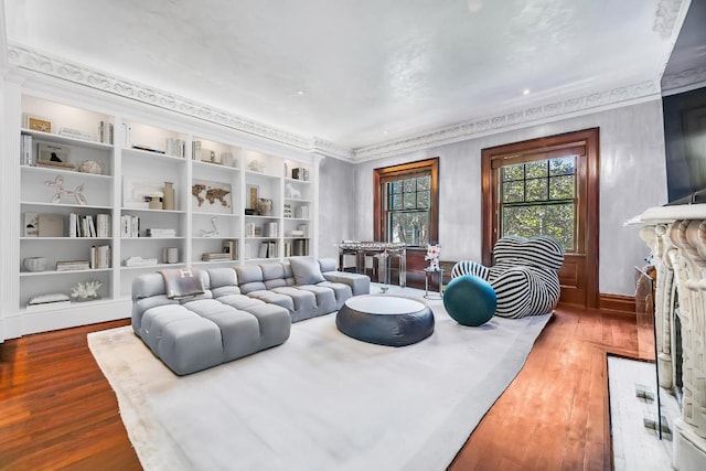 living room featuring ornamental molding, a fireplace, wood finished floors, and built in shelves