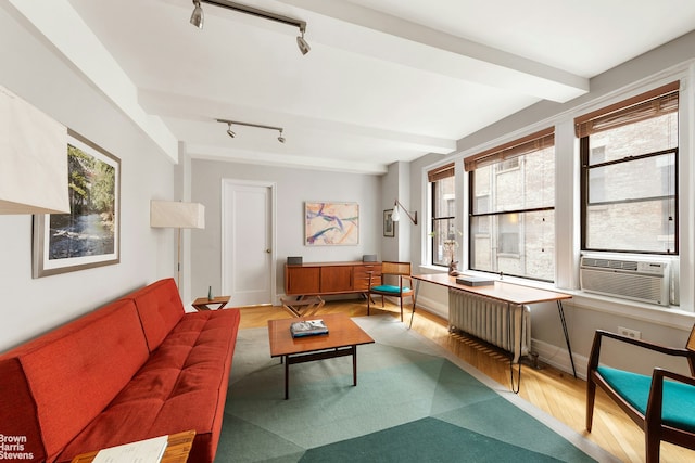 living area featuring beamed ceiling, cooling unit, wood finished floors, and radiator