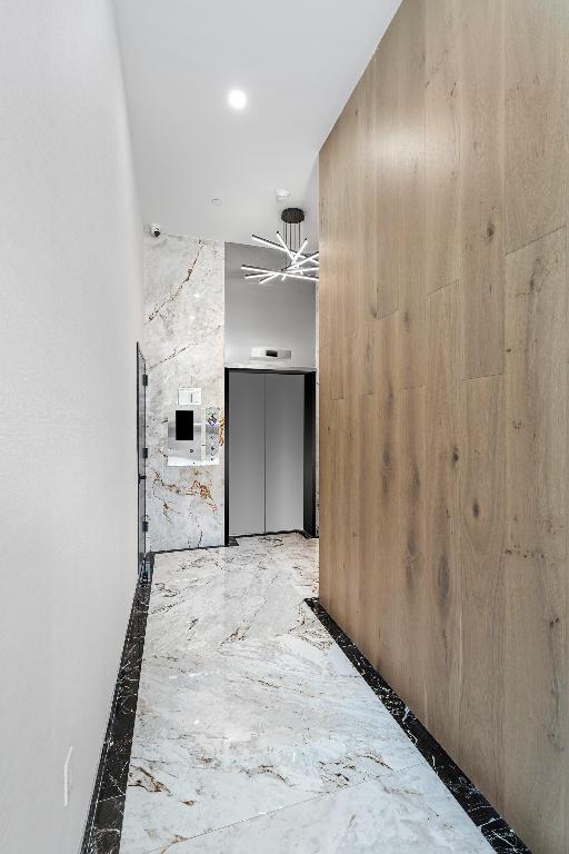 hallway featuring marble finish floor and elevator