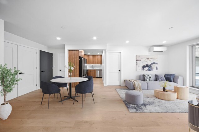 dining space featuring a wall mounted AC and light hardwood / wood-style flooring