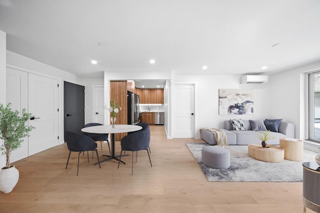 living room with a wall mounted air conditioner, recessed lighting, and light wood finished floors